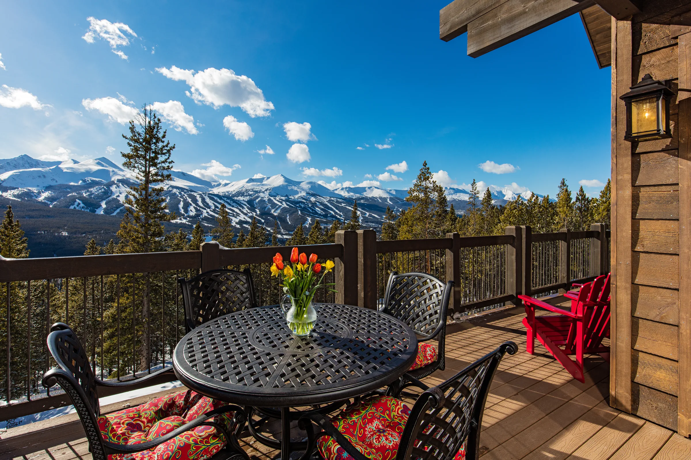 Sunny mountain home deck with views of snow-covered peaks